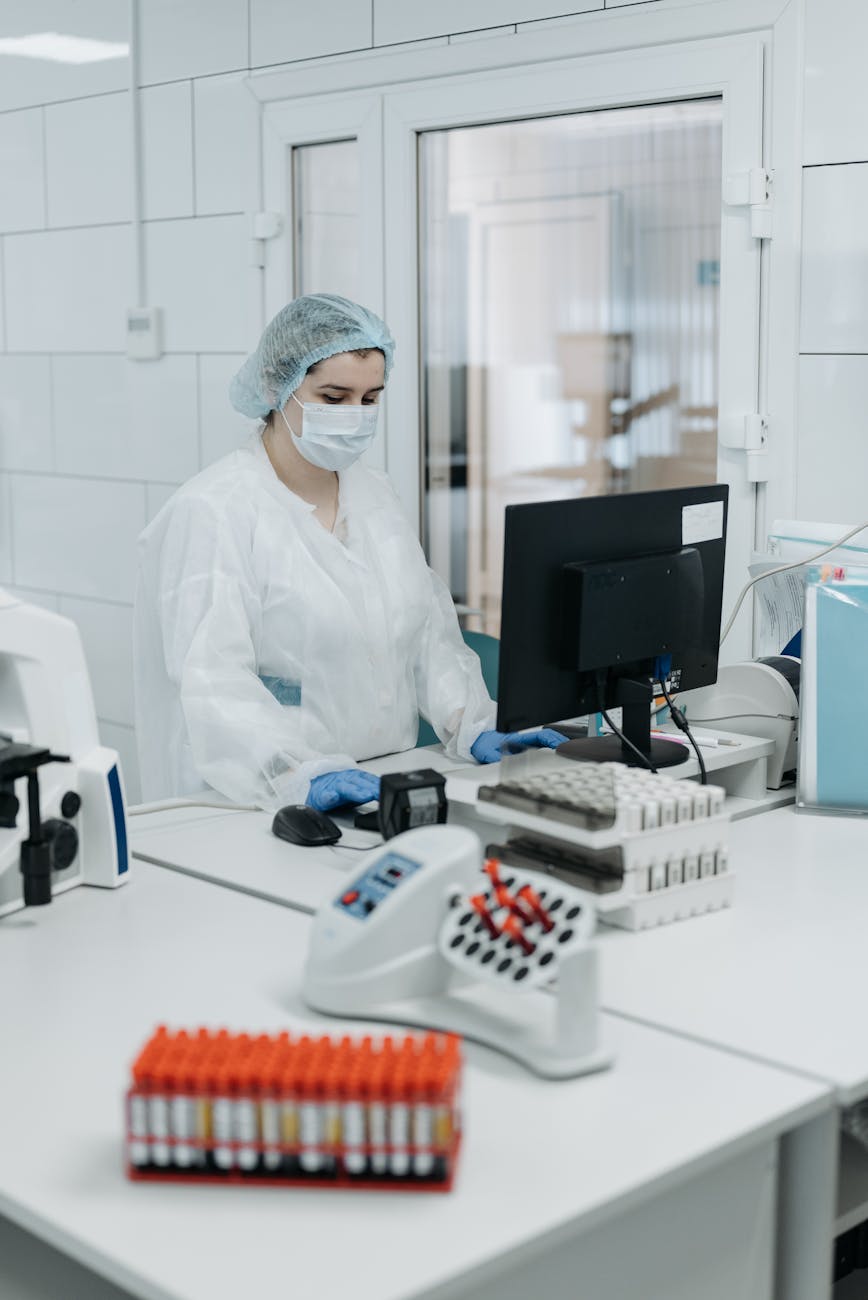 Woman in protective gear analyzing data in a laboratory setting.